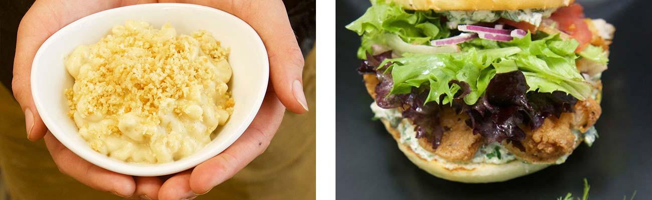 Hands present a serving of macaroni and cheese on the left, and a fried fish sandwich on the right at Secret Sandwich Society in Fayetteville, West Virginia.
