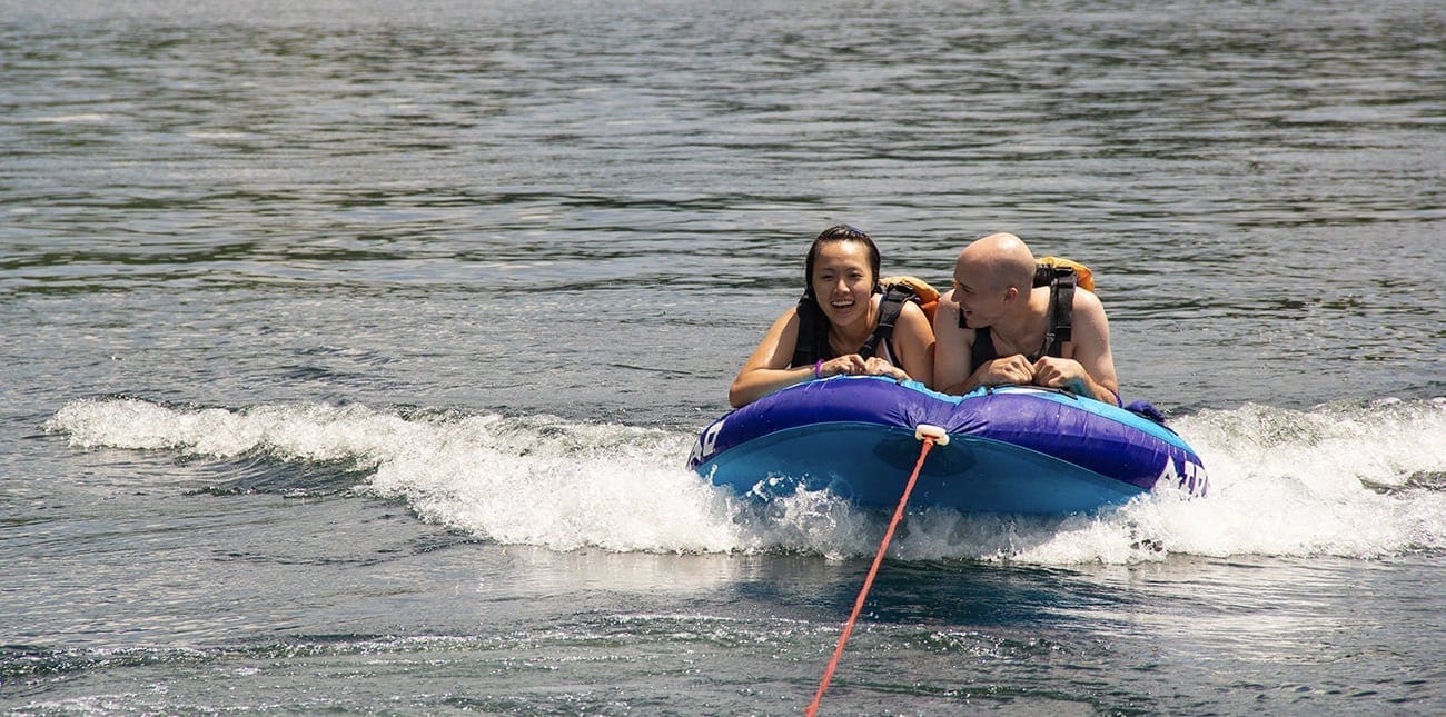 Guests of ACE Adventure Resort ride a speeding inflatable towed by a pontoon boat on the Summersville Lake Multi-sport Adventure Trip.