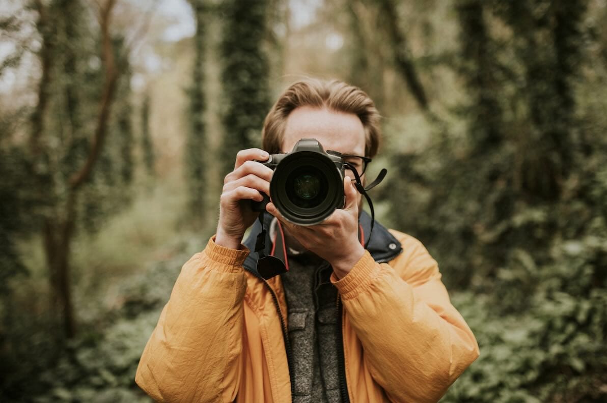 photographer with camera taking photo in the woods